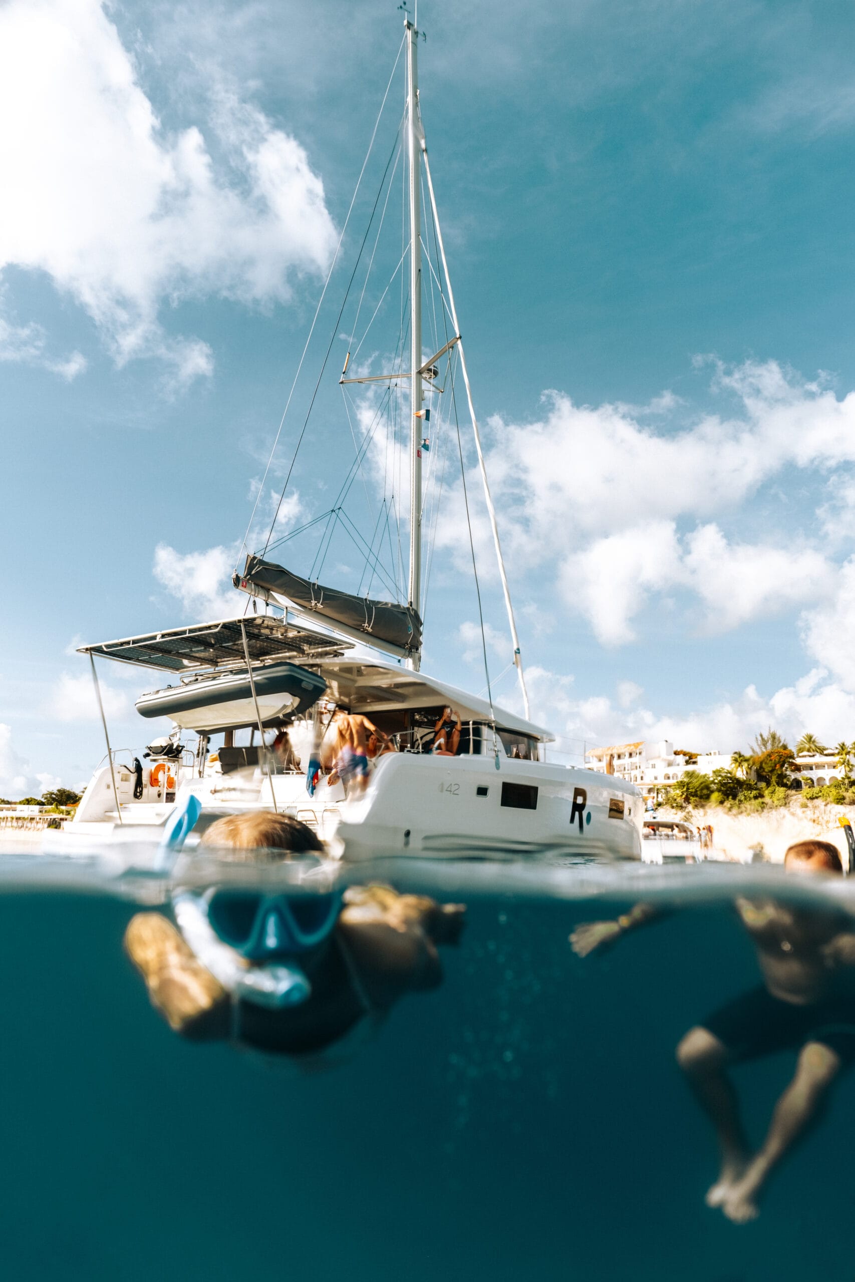 Two children snorkeling near Creole Rock, private catamaran is visible in the background.